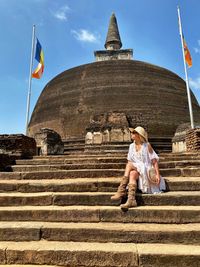 Full length of woman sitting on steps at historic place