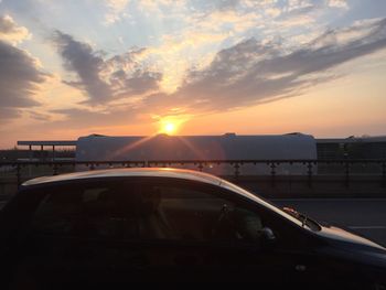 Cars on road against sky during sunset