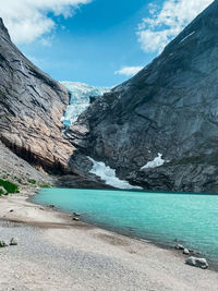 Scenic view of lake by snowcapped mountains against sky