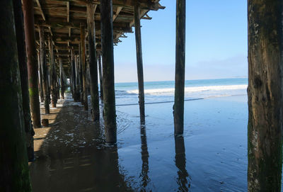 Landscape of water and poles taken under a wooden pier in santa cruz, california