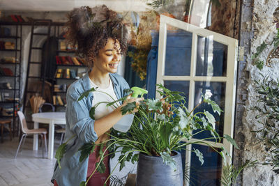 Portrait of smiling young woman standing by window