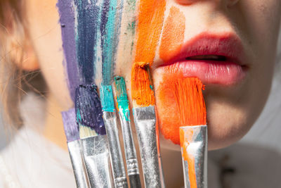 Close-up of young woman painting face and lips