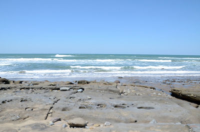 Scenic view of beach against clear blue sky