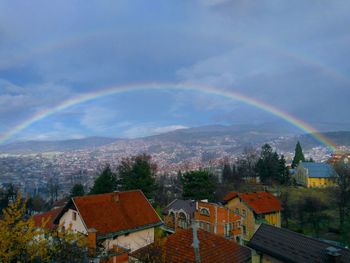 Rainbow over houses against sky