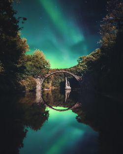 Reflection of trees in lake against sky at night