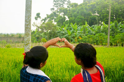 Rear view of mother and daughter against plants