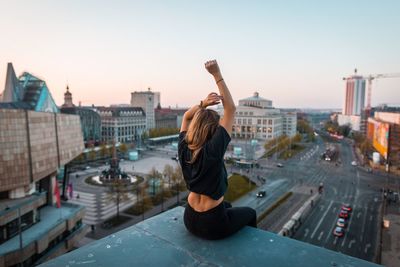 Rear view of woman with arms raised above city