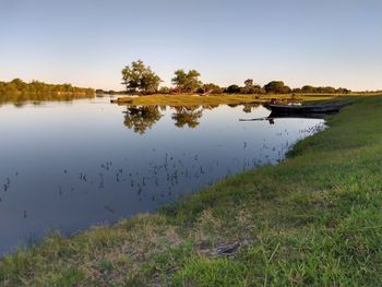 Scenic view of river bank against clear sky with reflection of trees in water