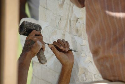 Cropped hands of artist carving wall