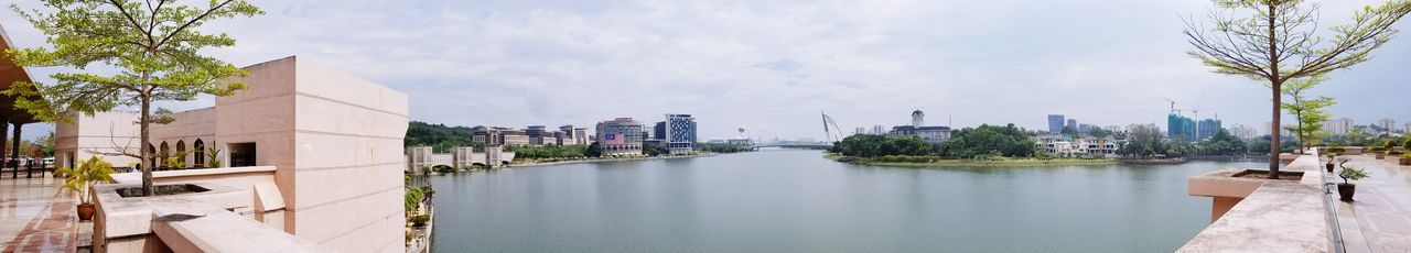 Panoramic view of buildings by river against sky