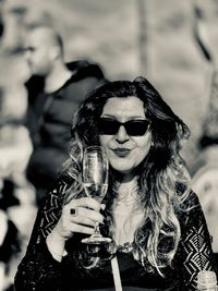 Portrait of a smiling young woman holding sunglasses