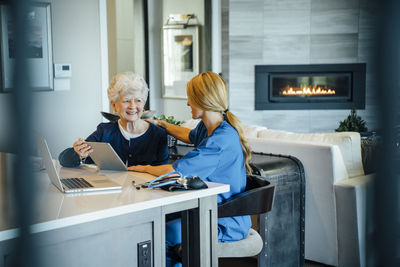 Senior woman using tablet computer with home caregiver