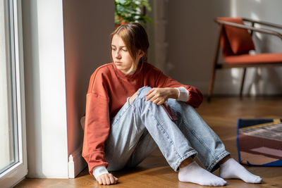 Upset teenage girl sit on floor suffer worried about bullying at school, bad relations with parents