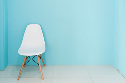 Empty chair against white wall at home