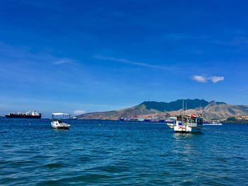 Boats sailing in sea against blue sky