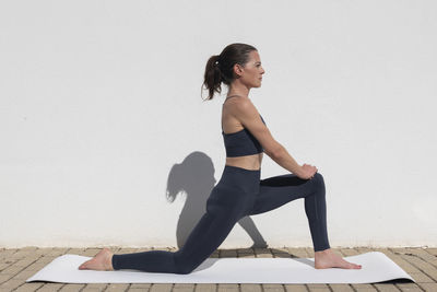 Side view of young woman exercising at home