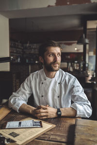 Confident chef sitting at table in restaurant