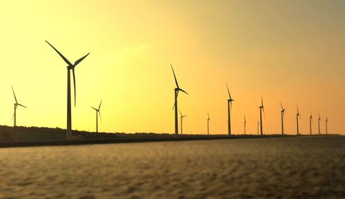 Windmills against sky during sunset