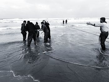 People photographing on beach against sky