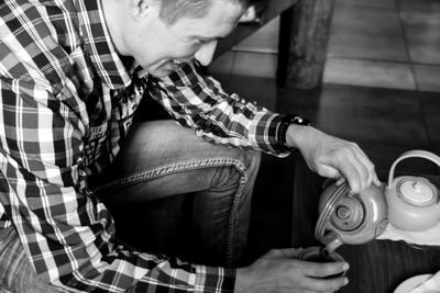 High angle view of man pouring coffee from kettle in cup at cafe