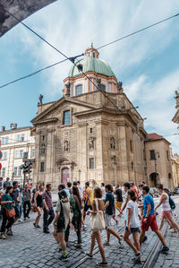 People walking on street against church in city