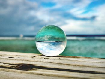 Close-up of crystal ball on sea against sky