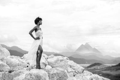 Man standing on rock against sky