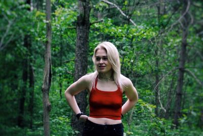 Young woman standing against trees at forest