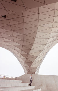 Man walking on bridge against sky