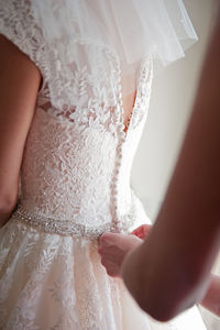 Cropped hands adjusting wedding dress of bride