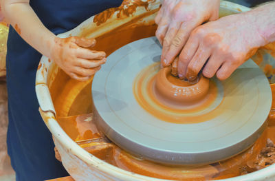 Girl and man making mud product on pottery wheel