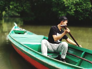 Young man sailing boat in lake