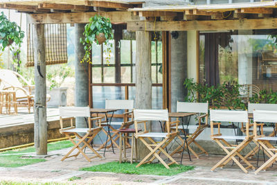 Empty chairs and table against window of old building