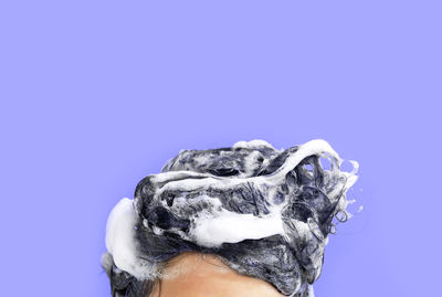 Female head with hair in foam close-up on a purple background.