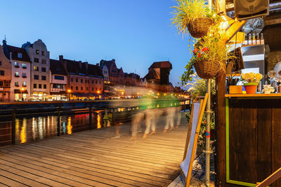 Illuminated buildings by river against sky at night