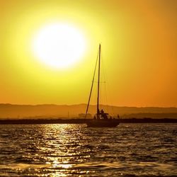 Sailboat sailing in sea at sunset