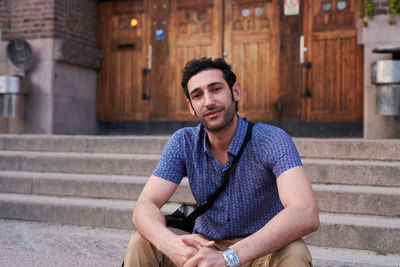 Portrait of confident male student sitting outside language school