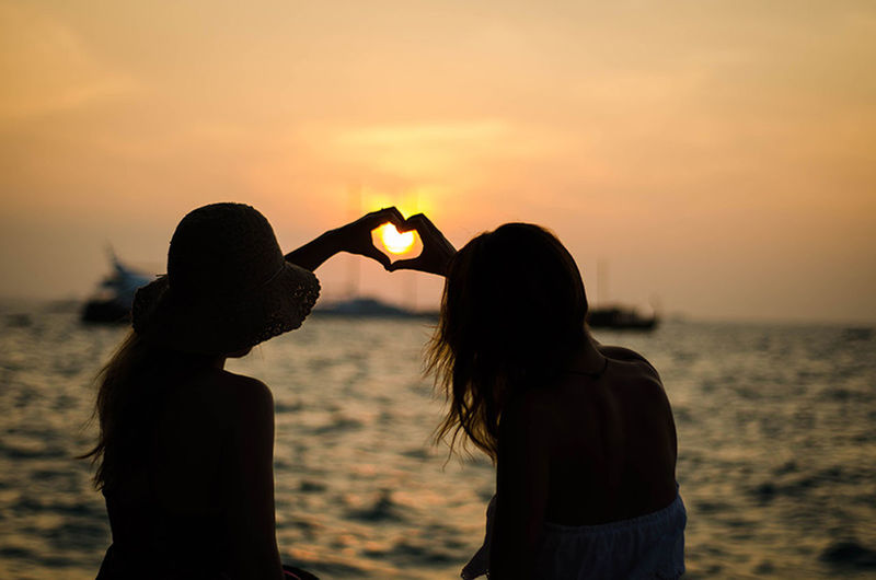 sunset, leisure activity, lifestyles, rear view, sky, focus on foreground, holding, beach, standing, childhood, person, sea, sun, nature, water, men, beauty in nature, shore