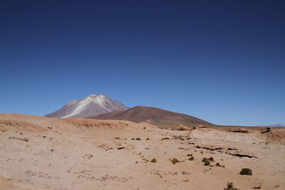 Scenic view of desert against clear blue sky