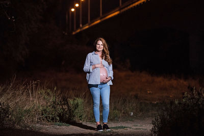 Full length portrait of woman standing at night