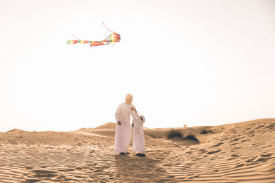 Full length of father with son flying kite in desert