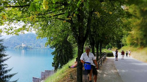 People by lake against trees