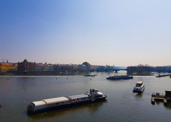 Boats in river by city against clear sky