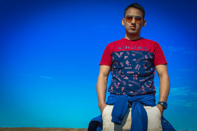 Portrait of mid adult man sitting against blue sky