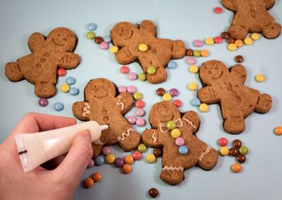 High angle view of gingerbread cookies on table being decorated with icing and smarties