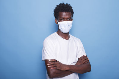 Portrait of man wearing mask against blue background