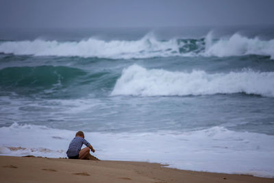 Kid plays on shore of huge, raging ocean. childhood freedom and adventure. discovery of the world