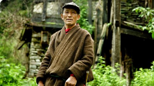 Portrait of man standing against abandoned building