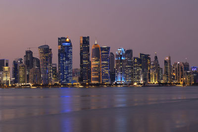 Illuminated buildings in city against sky at night