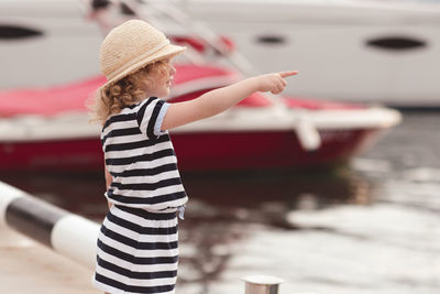 Girl in hat pointing at sea